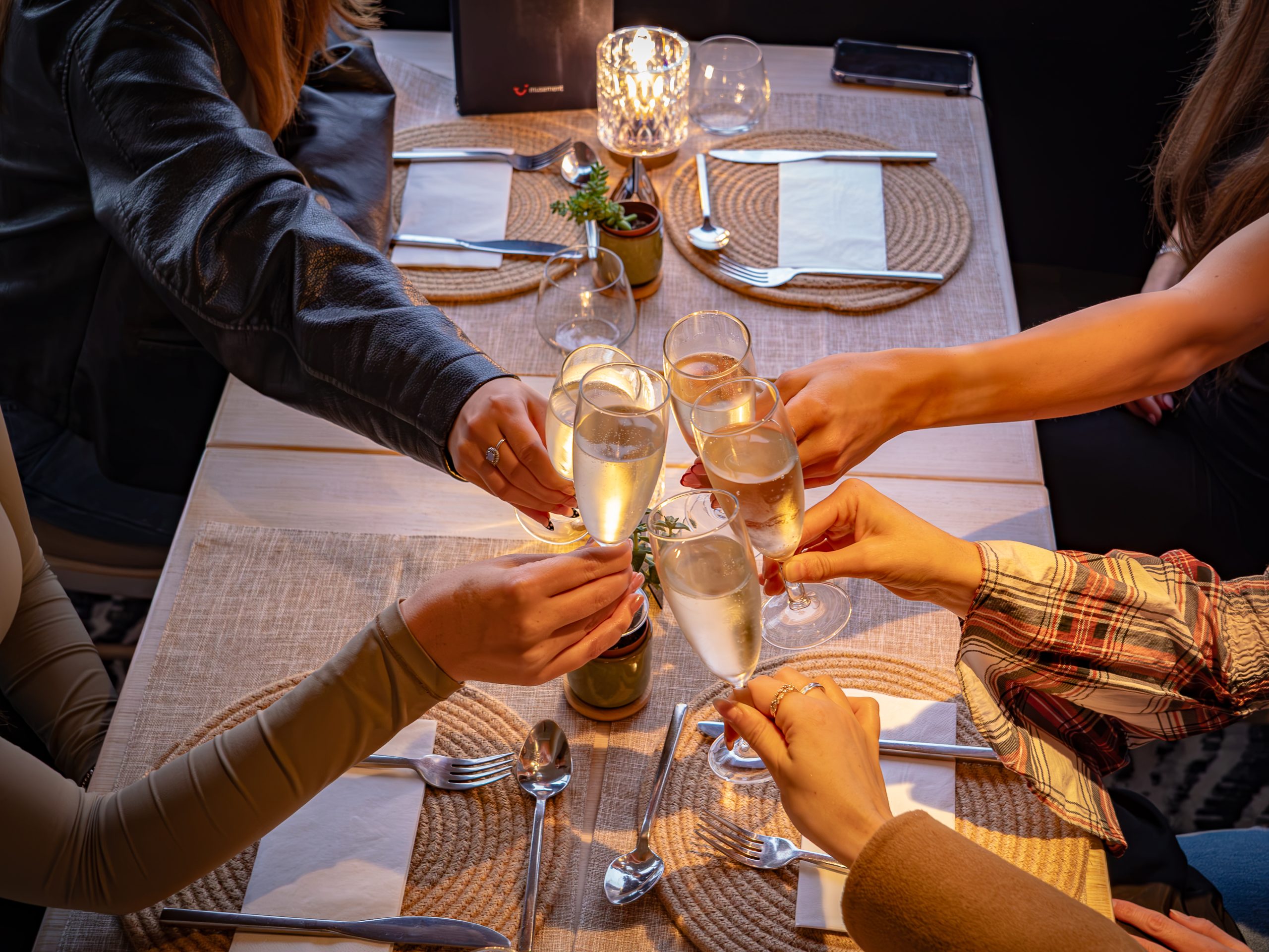 Friends toasting with champagne glasses around a set dining table.