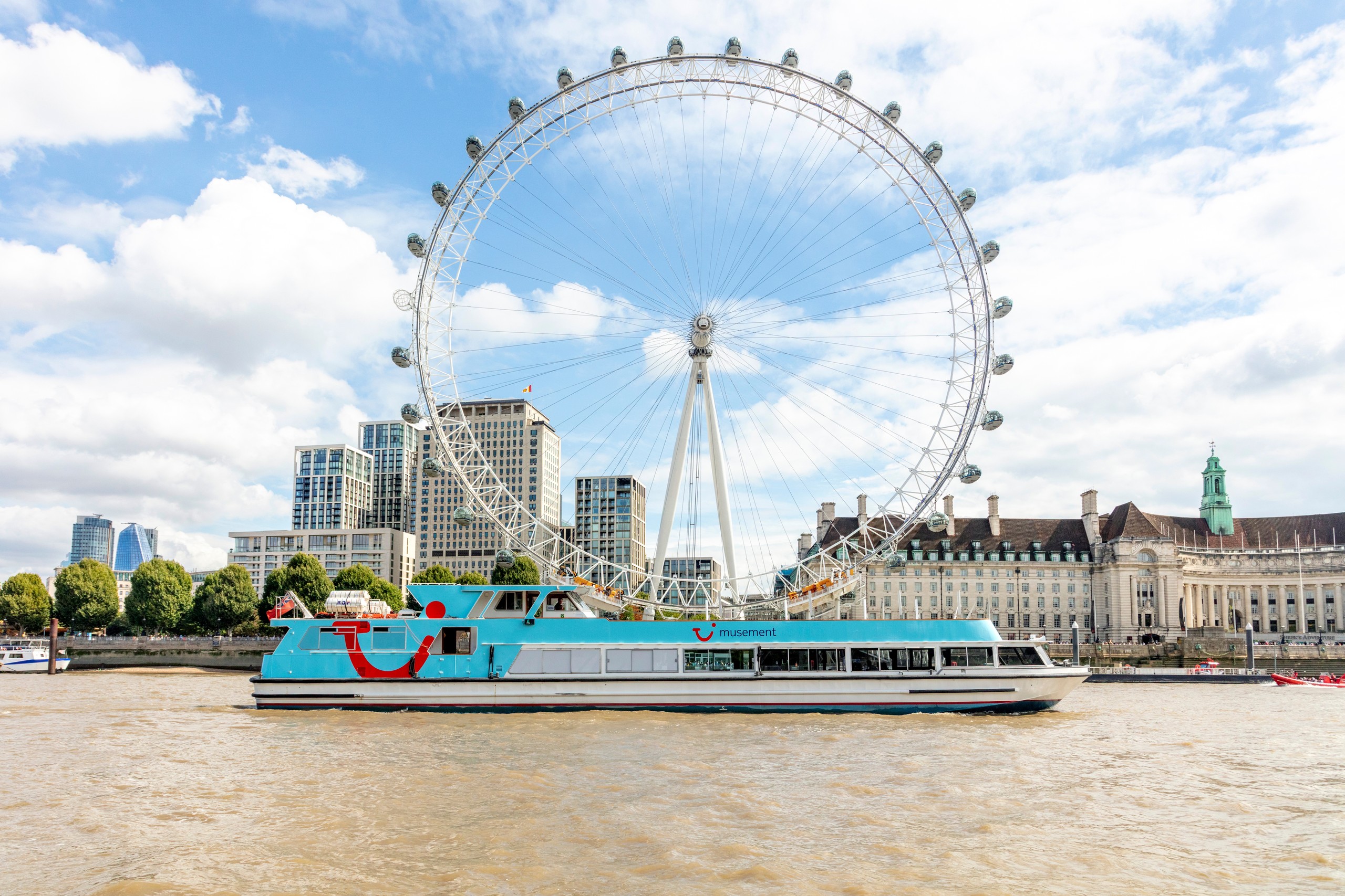 Boat on river with London Eye and cityscape in background.