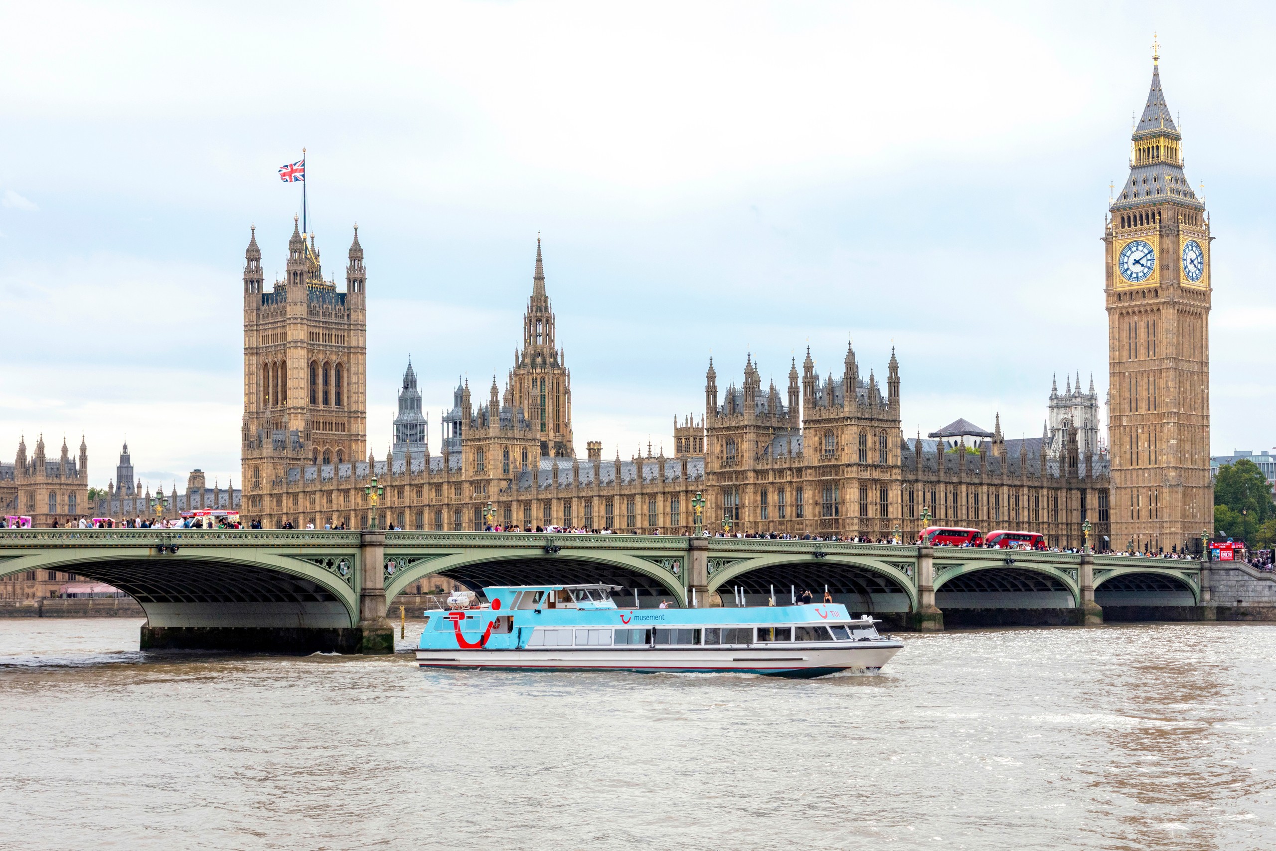 View of the Houses of Parliament and Big Ben with a boat on the River Thames.