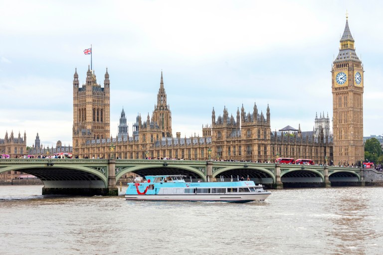 View of the Houses of Parliament and Big Ben with a boat on the River Thames.