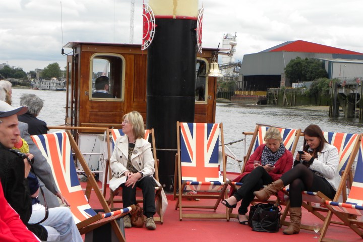 People sitting on deck chairs with Union Jack design on a boat.