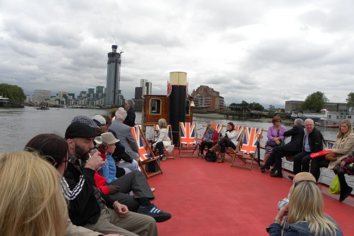 People sitting on a boat deck with Union Jack chairs on a cloudy day.