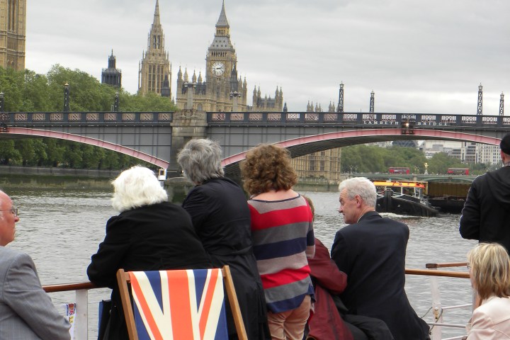 People on a boat near Westminster Bridge with Big Ben in the background, cloudy sky.
