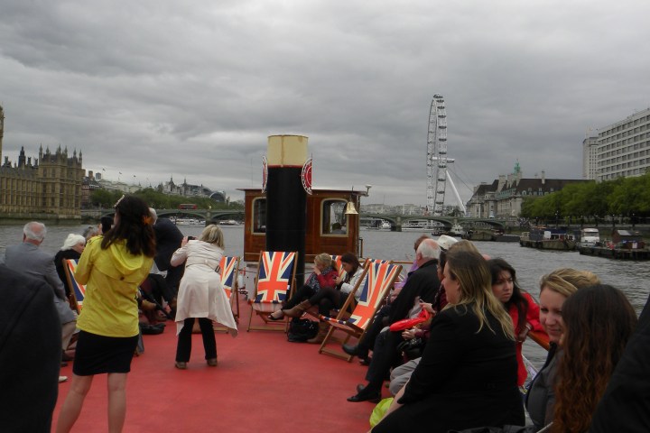 People on a boat deck with Union Jack chairs, London Eye and Big Ben in the background.