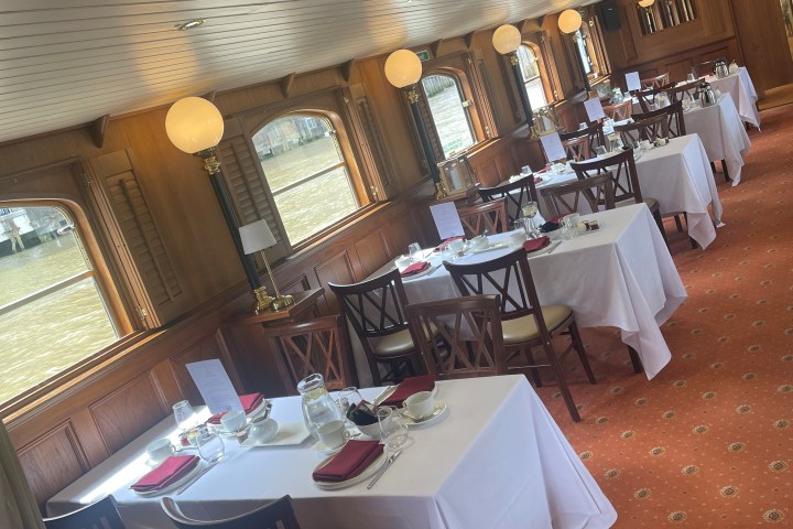 Elegant dining room on a boat with set tables and wooden decor.