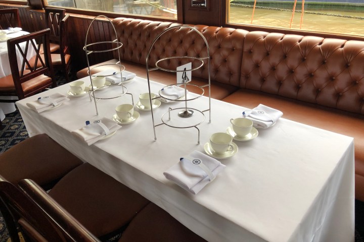 Table set for tea with empty tiered stands, cups, and napkins on a boat.