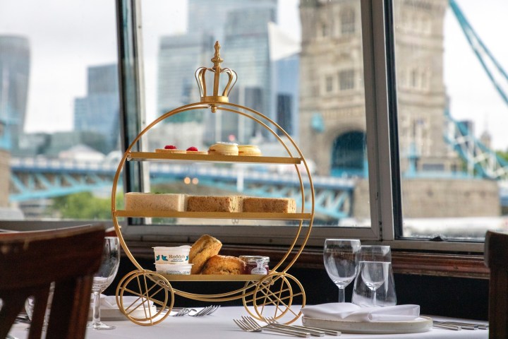 Afternoon tea stand by window with cityscape and bridge view.